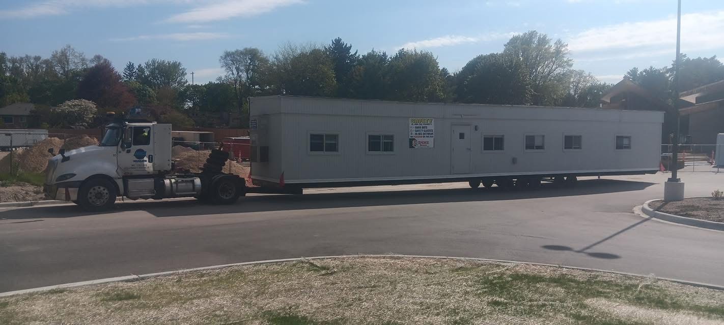 Joe’s Transporting truck hauling a long modular office trailer